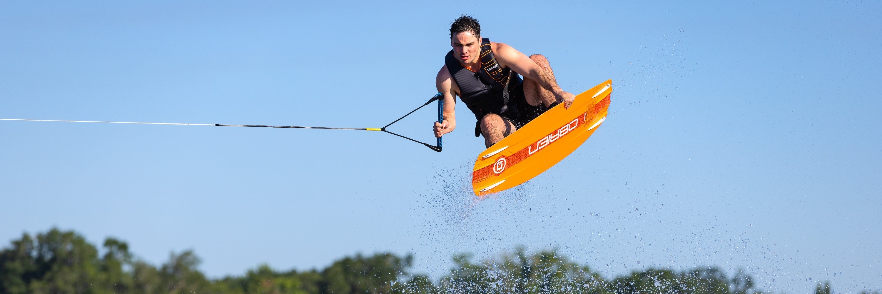 Man in the air jumping an orange wakeboard