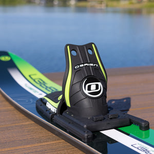 Black and green water ski on a wooden dock with water in the background