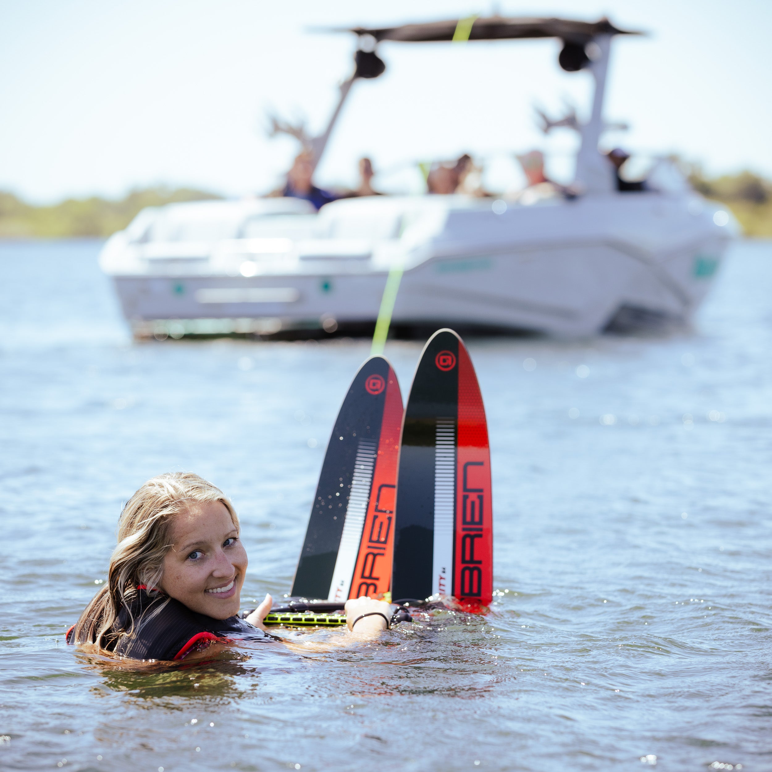 Person in the water with two water skis and a boat in the background on a lake
