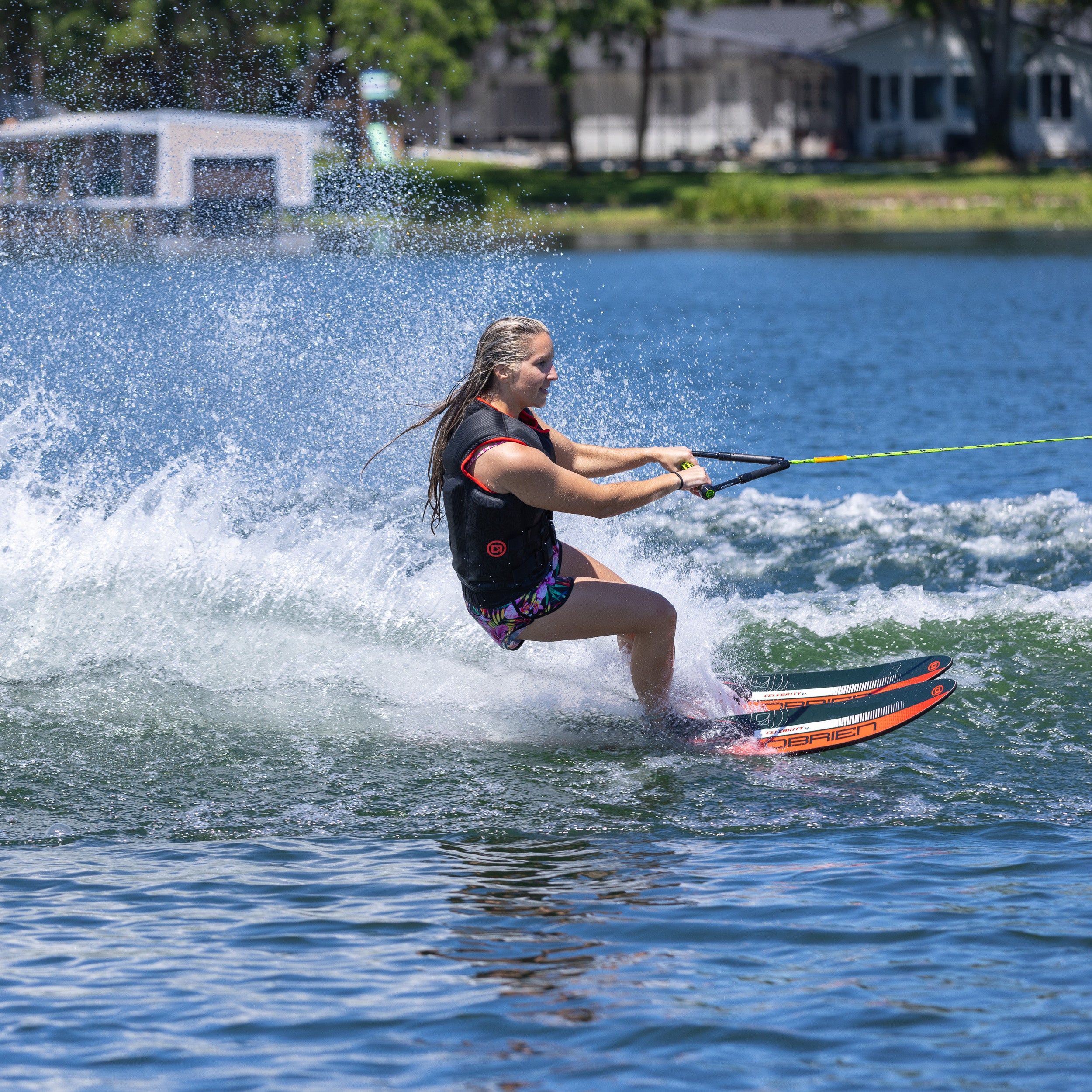 Person water skiing on a lake with houses and trees in the background