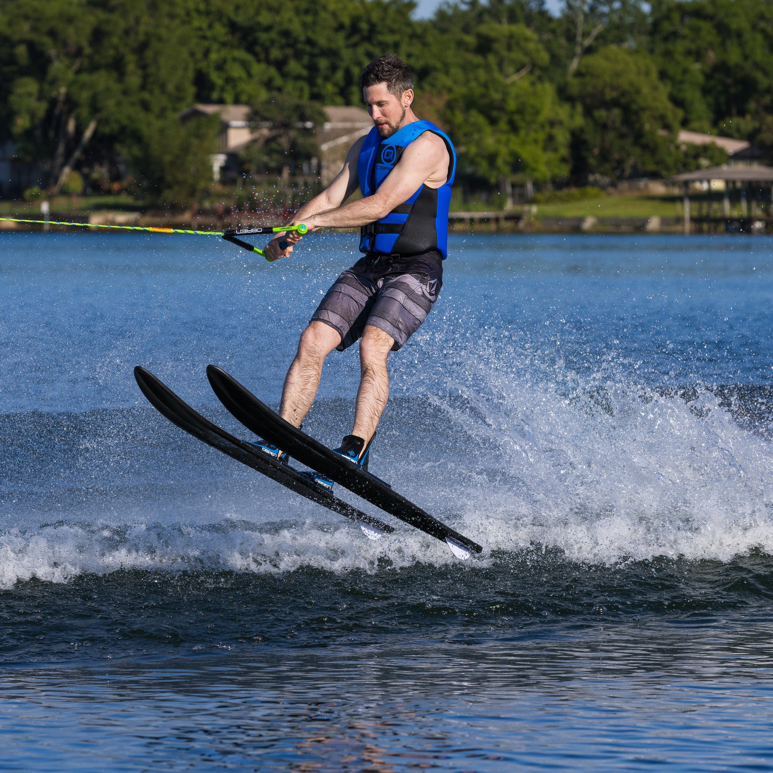 Person water skiing on a lake with trees and houses in the background
