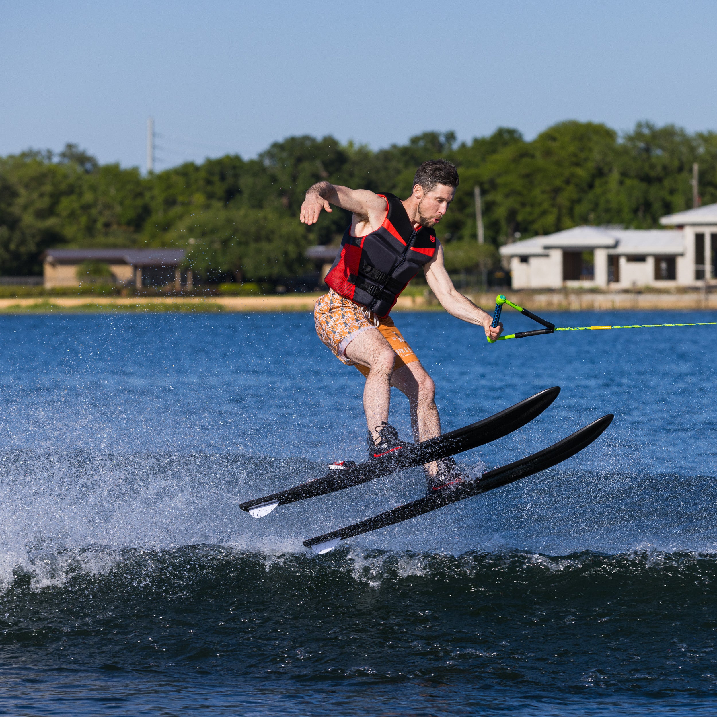 Person water skiing on a lake with trees and buildings in the background