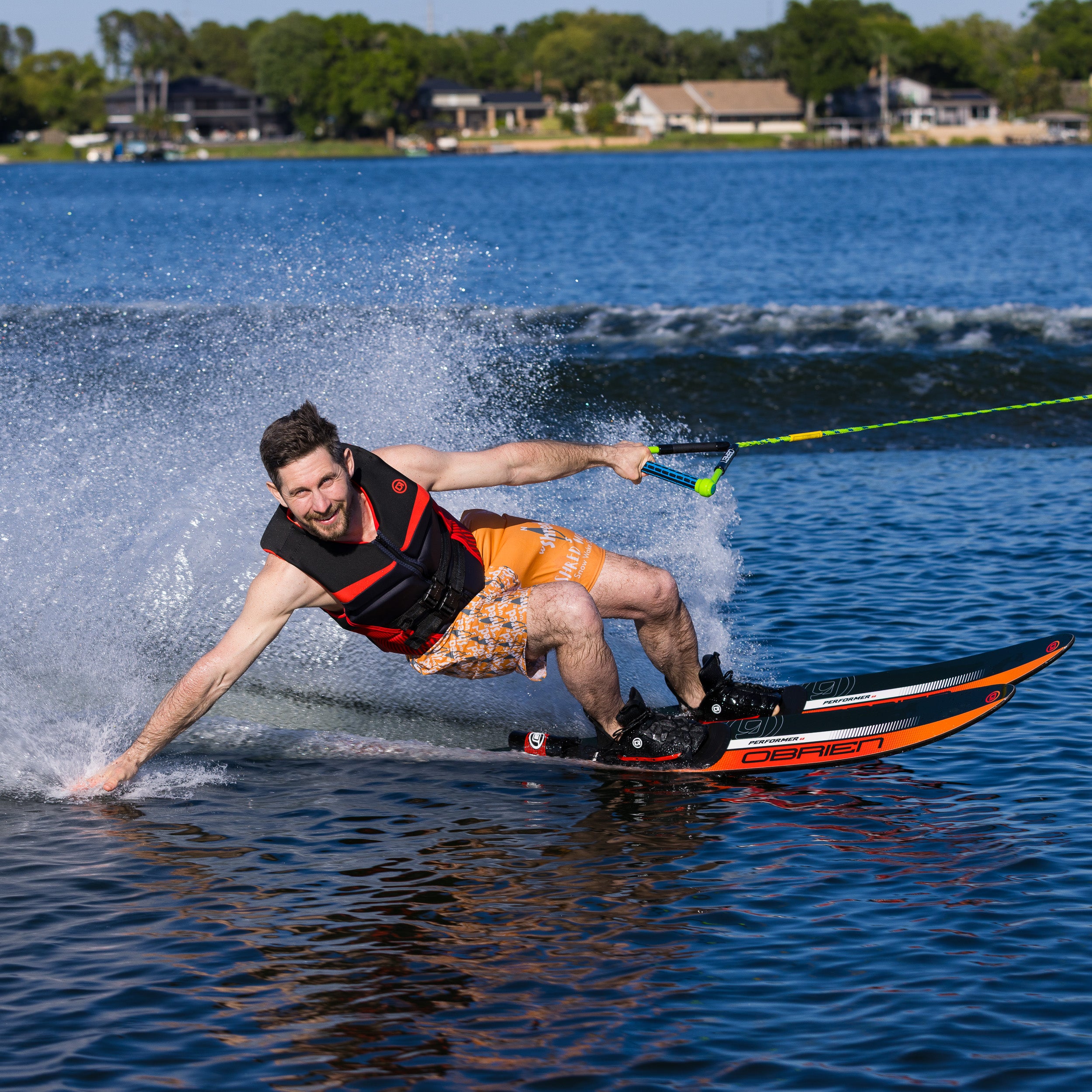 Man water skiing on a lake with houses and trees in the background