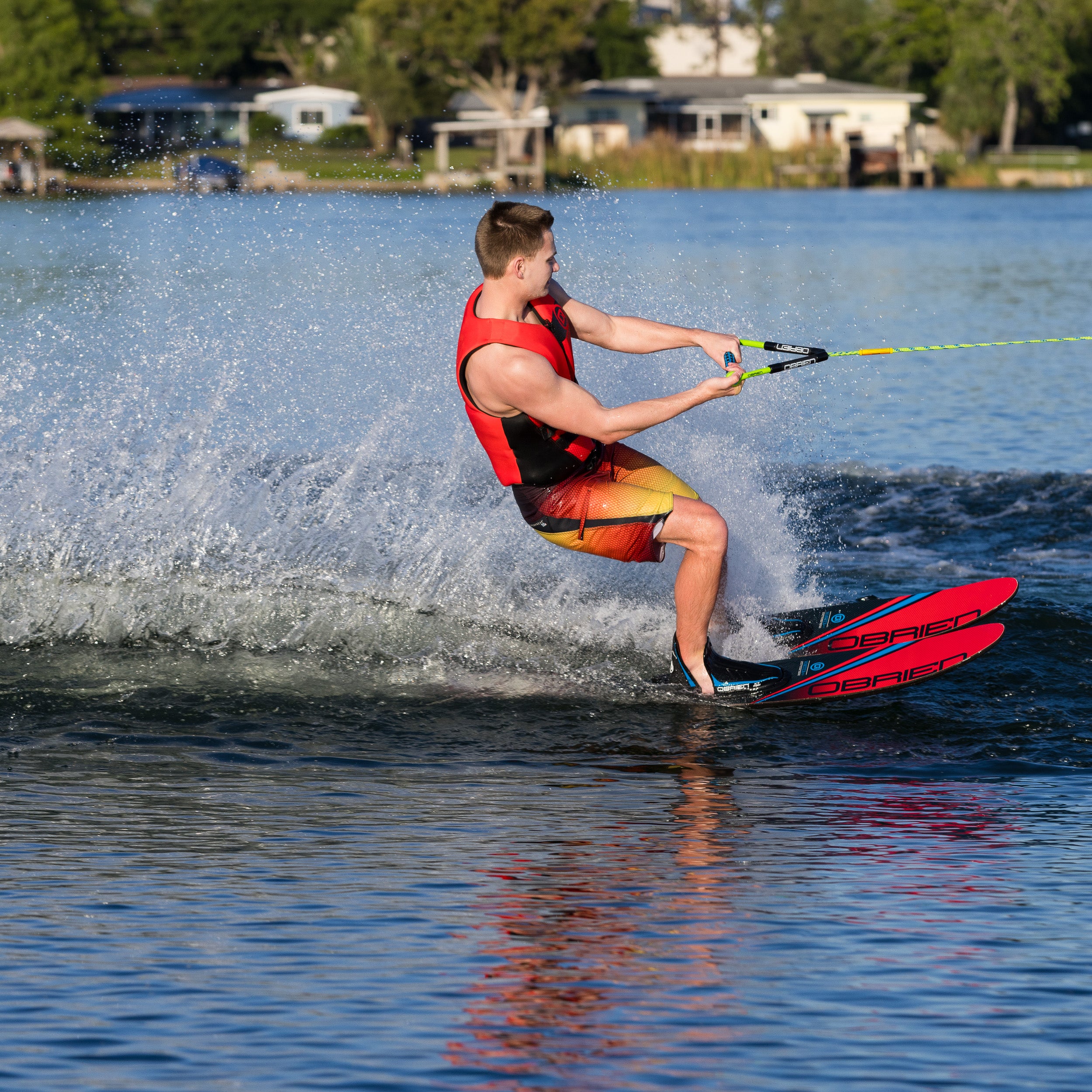 Person water skiing on an O'Brien on a lake with houses and trees in the background